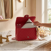 Bag-a-Vie herringbone petite handbag shaper pillow being placed inside a red quilted luxury purse on a marble vanity.